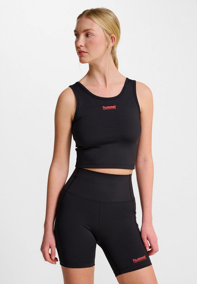 Svart atletisk crop top och högmidjade shorts tillverkade av stretchigt material, med en röd logotyp framtill och på sidan. Slät textur.