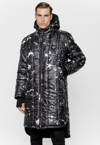 Pikowana długa czarna kurtka puchowa z białym wzorem plam, z suwakiem z przodu, kapturem i czarnymi mankietami. Teksturowany połyskliwy wykończenie.