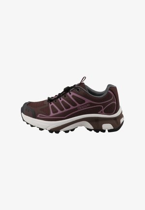 Scarpa da trail running marrone scuro e viola con lacci neri, suola con grip texturizzato e intersuola ammortizzata bianca e marrone.