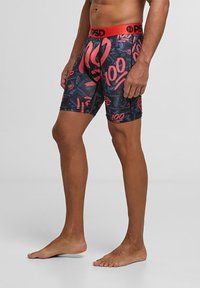Boxers en jersey pour homme dans un design ajusté, avec une base noire ornée de graphiques rouges audacieux et une taille rouge. Fabriqués en tissu extensible pour un confort optimal.