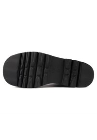 Semelle de chaussure noire avec des motifs de profondeur et des indications de taille "L 37" et "37" visibles au centre.