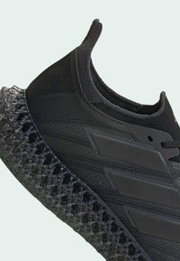 Sort atletiksko med en vævet tekstiloverdel og en gennemsigtig, gitterlignende 3D-printer sål med teksturerede detaljer.