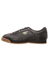 Svart Puma Roma lädersneaker med gummisula, snörning och guld Puma-logotyp på sidan.