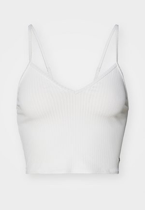 Bijela rebrasta kratka majica s podesivim trakama i V izrezom. Ima glatku teksturu i prilagođen siluetu.