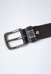 Ceinture en cuir noir avec une boucle en métal argenté, présentant un nom de marque gravé, une texture lisse et un détail de bouton-pression en métal.