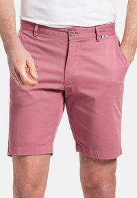 Roze katoenen shorts met een vlakke voorkant,Regular fit en zijzakken. Beschikt over een bruine knop en een kleine driekleurige accent op de tailleband.