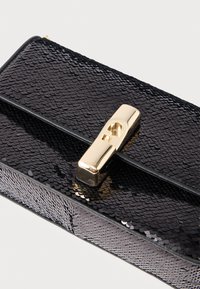 Sort håndtaske med pailletter, udstyret med en lås i guldfarvet metal, rektangulær form og glatte læderdetaljer. Den teksturerede overflade tilføjer visuel interesse.