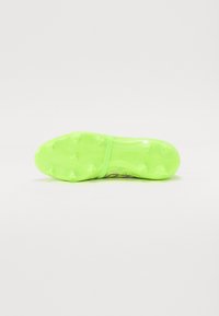 Crampon de football vert avec une semelle texturée dotée de pointes moulées, conçu pour une traction optimale, et un détail de marque sur le côté.