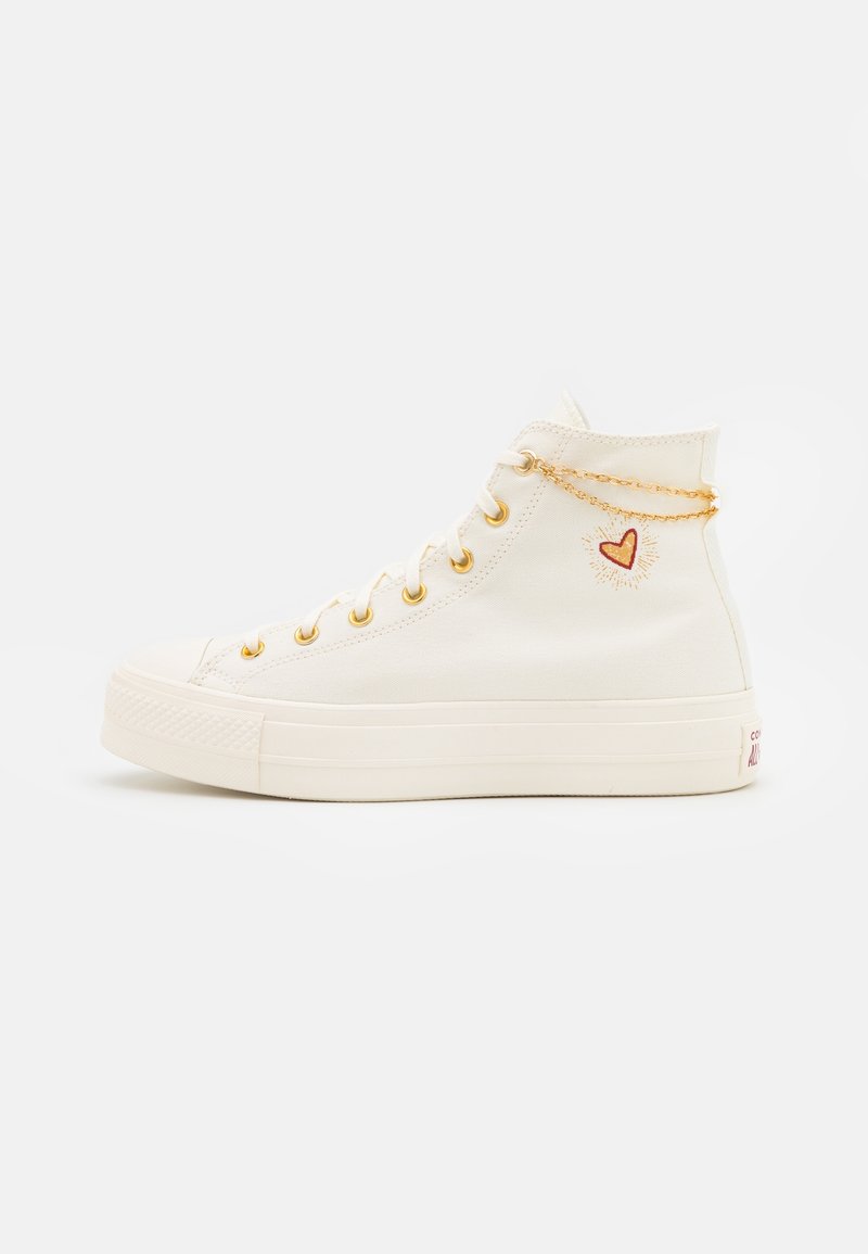 Hög sneaker i canvas i off-white med guldfärgade snörhål, hjarformad design och kedjedetalj. Har en gummisula och strukturerad tån. 