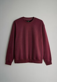 Bordowy pulower z długimi rękawami, okrągłym dekoltem i ściągaczami przy mankietach. Gładka faktura, prosty design bez wzorów i dodatków.