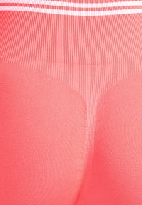Leggings de tiro alto y canalé en un vibrante color rosa con una textura suave. Presentan una franja blanca contrastante a lo largo de la cintura.