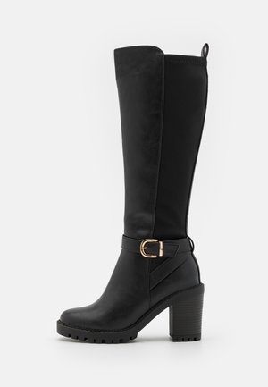 Black knee-high boots made of smooth synthetic leather. Features a thick block heel, buckle accent, and textured sole for grip.