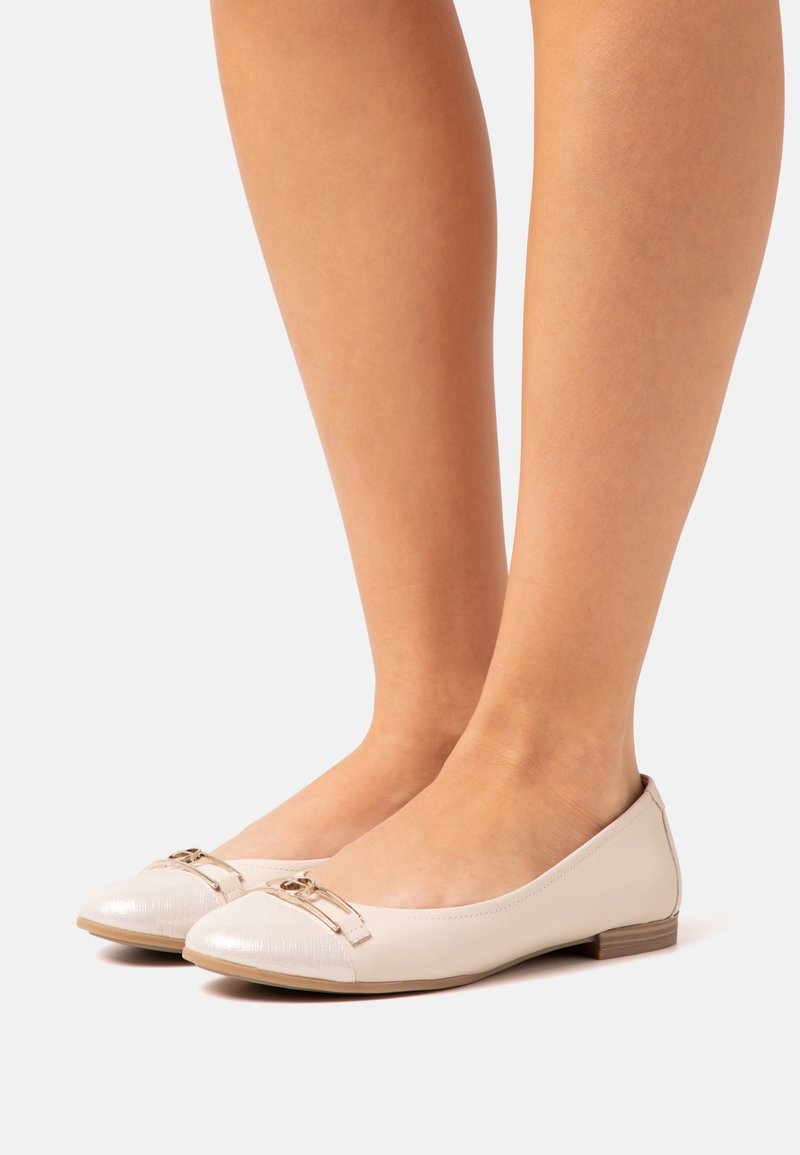 Scarpe flat beige con punta rotonda, pelle testurizzata e punta lucida, accentuate da un dettaglio in fibbia metallica nella parte frontale.