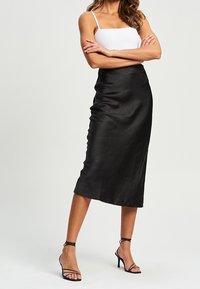 Midiruokaa mustasta satiinista, jossa on sileä tekstuuri, muotoiltu malli ja herkkä kiilto. Yhdistetty valkoiseen ribbimäiseen toppiin ja mustiin remmikenkiin.