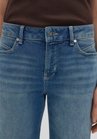 Blauwe denim jeans met een lichte vervaging, klassieke vijfzakken ontwerp, metalen knoopsluiting en contrasterende stiksels.