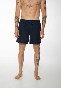 Shorts de bain bleu marine avec taille élastique à cordon de serrage et poches latérales, fabriqués en tissu léger. Comprend un patch de logo sur l'ourlet gauche.