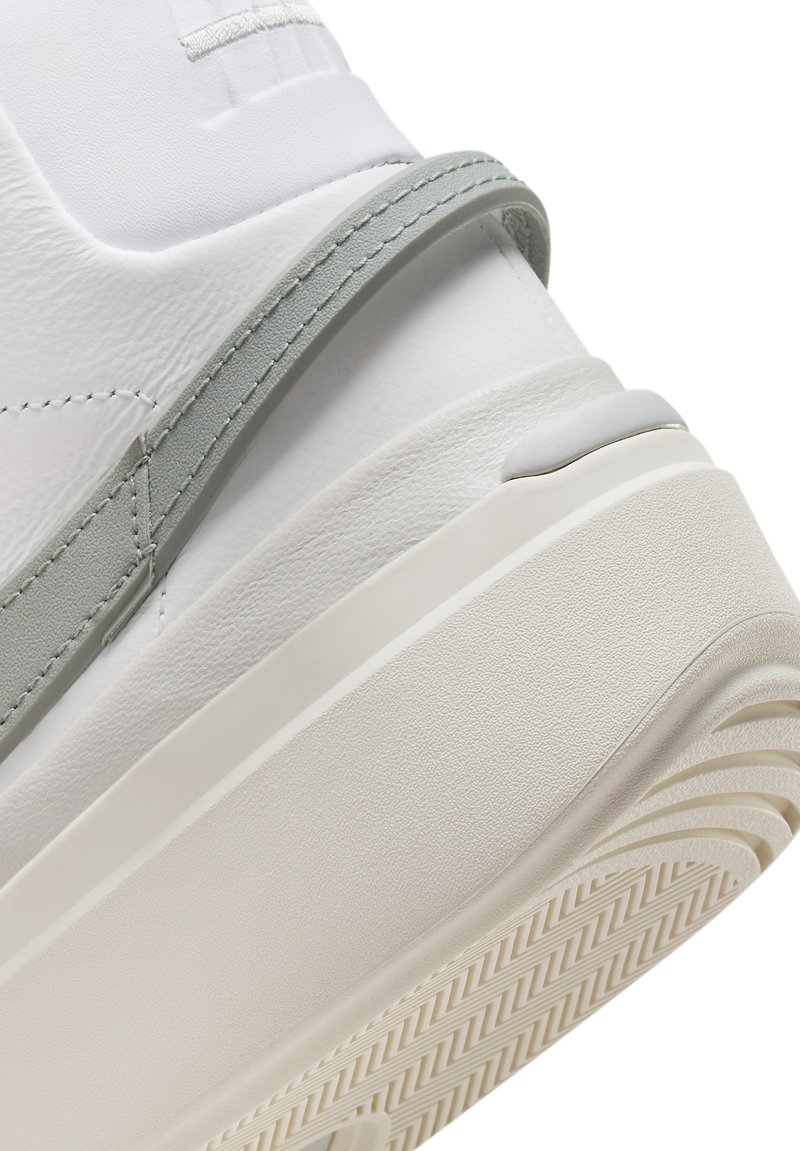 Sneaker bianco in pelle con dettagli grigio chiaro, superficie strutturata, suola di gomma spessa e design del battistrada decorato; progettato per il comfort.