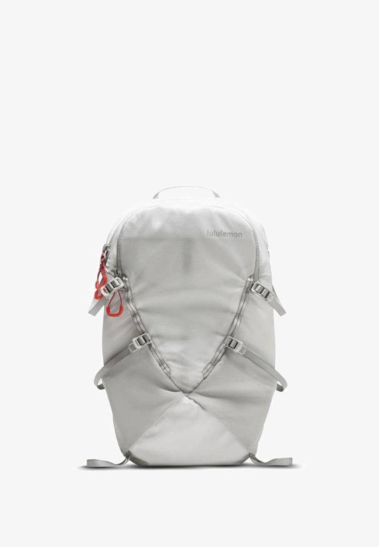 Sac à dos gris clair en tissu lisse et texturé, doté de bretelles réglables, d'une poignée supérieure et de garnitures rouges pour un accès facile.