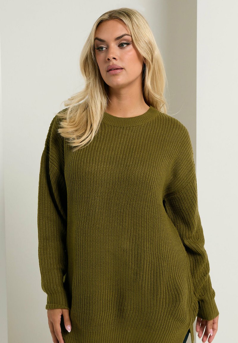 Pull en tricot vert olive avec une coupe décontractée, texture côtelée, col rond et manches longues ; présente des fentes sur les côtés à l'ourlet.