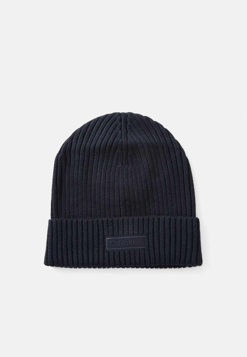 Navy knitted beanie with ribbed texture and cuff. Features a rectangular Calvin Klein logo patch on the front.