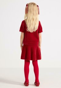 Red fluffy sweater and skirt set, paired with bright red tights and shiny red shoes. Long blonde hair with red ribbon accents.