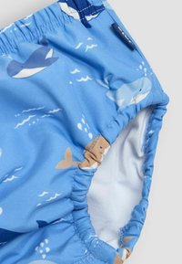 Blå svøm shorts med mønster af hvaler og bølger. Elastisk talje og bølgerande kanter. Indersiden er hvid.