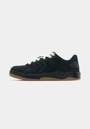 Baskets en daim noir avec lacets blancs, design supérieur en matelassage zigzag, bout rond et semelle en caoutchouc texturé couleur gomme. Présente un accent logo sur le côté.