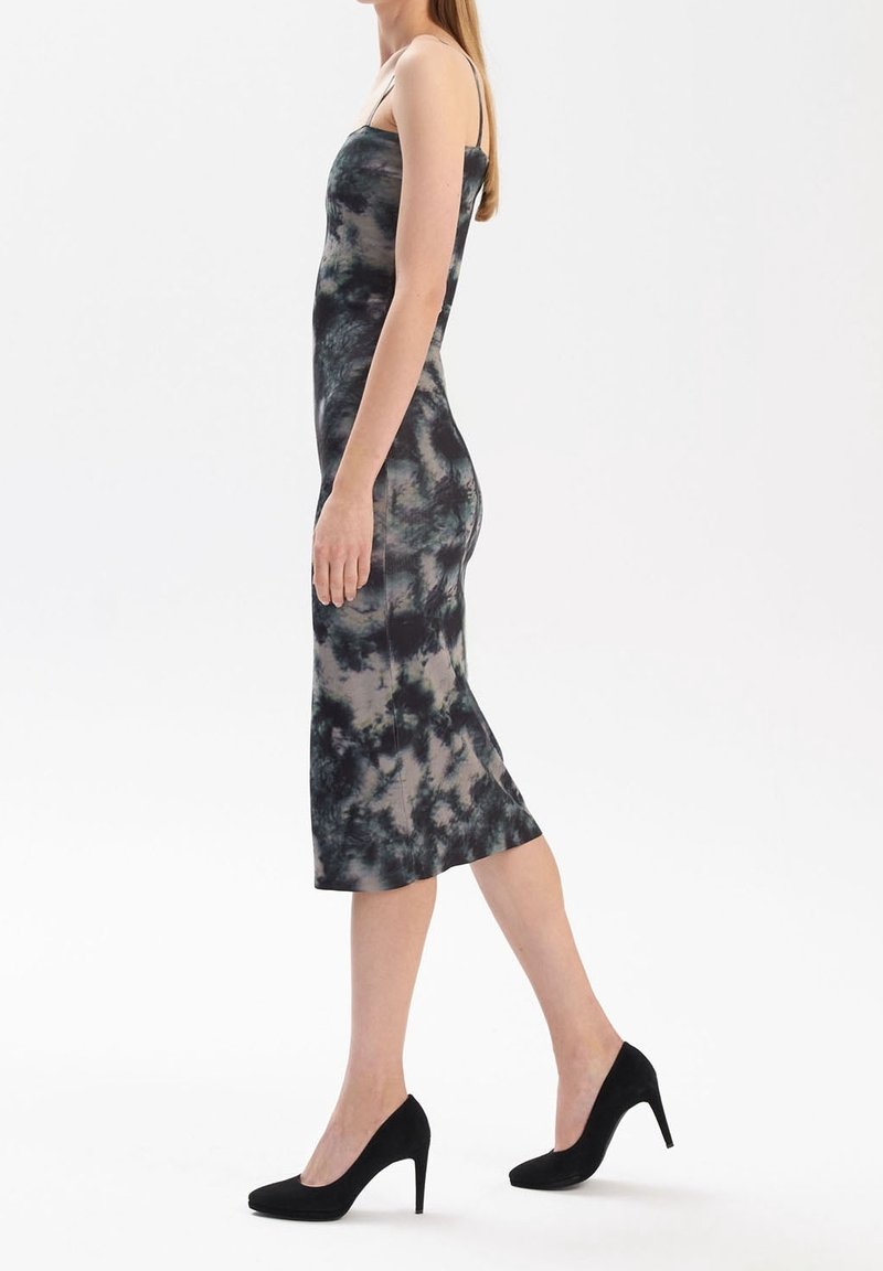 Abito midi tie-dye nero e grigio con spalline sottili, forma aderente e texture liscia. Indossato con scarpe con tacco nere.