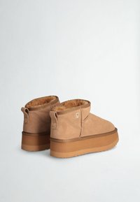 Tan suede ankle boots with faux fur lining, a flat rubber sole, and a small loop at the heel for easy wear. Classic design and comfortable.