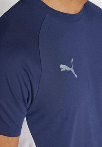 Marineblå kortærmet t-shirt lavet af blødt stof, med et reflekterende sølv Puma-logo på brystet og en rund halsudskæring.
