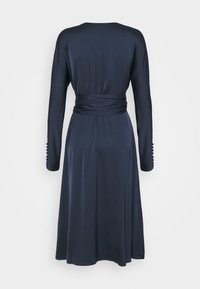 Robe bleu marine à manches longues, taille cintrée et boutons décoratifs sur les poignets. Texture lisse et coupe longueur genou.