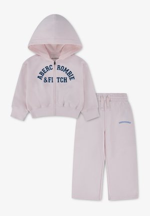 Jasnoróżowa dziecięca bluza z kapturem i zamkiem oraz pasujące spodnie, oba z niebieskim logo Abercrombie & Fitch.