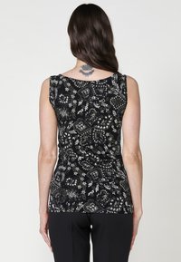 Débardeur noir sans manches avec des motifs floraux et paisley en blanc et vert doux. Tissu doux et extensible avec une silhouette ajustée.