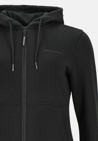 Zwarte hoodie met rits, gemaakt van zacht en textuurstof. Beschikt over een rits aan de voorkant, een verstelbare capuchon met trekkoord en een subtiele logo op de borst.