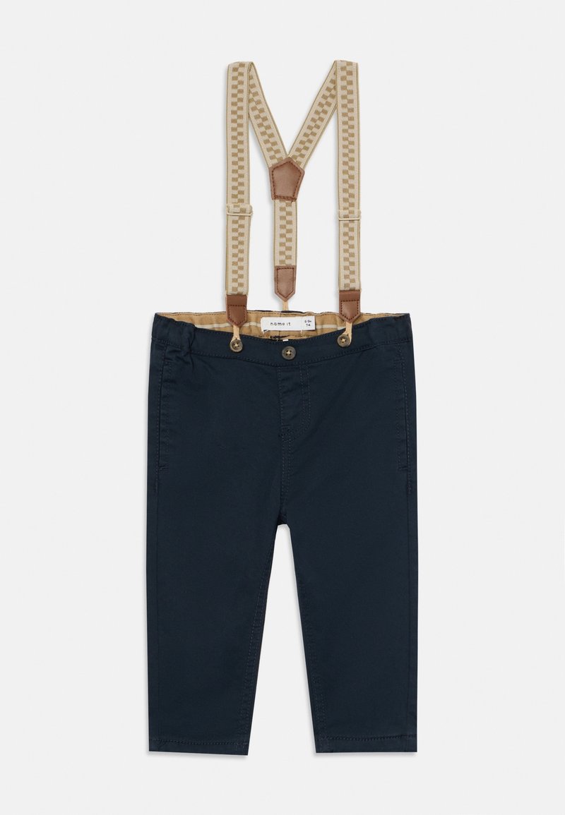 Pantalon bleu marine pour enfants avec bretelles beiges à motifs attachées par des patchs en cuir marron et des boutons.