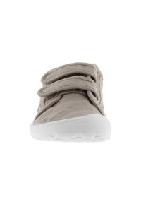 Beige tygsko med två tygremmar och en vit gummisula. Rund tådesign och strukturerad ovandel för grepp och komfort.