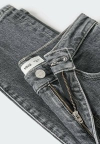 Jean en denim gris avec une fermeture éclair, un bouton en métal et une étiquette "MNG". Le tissu a une légère texture et une coupe classique.