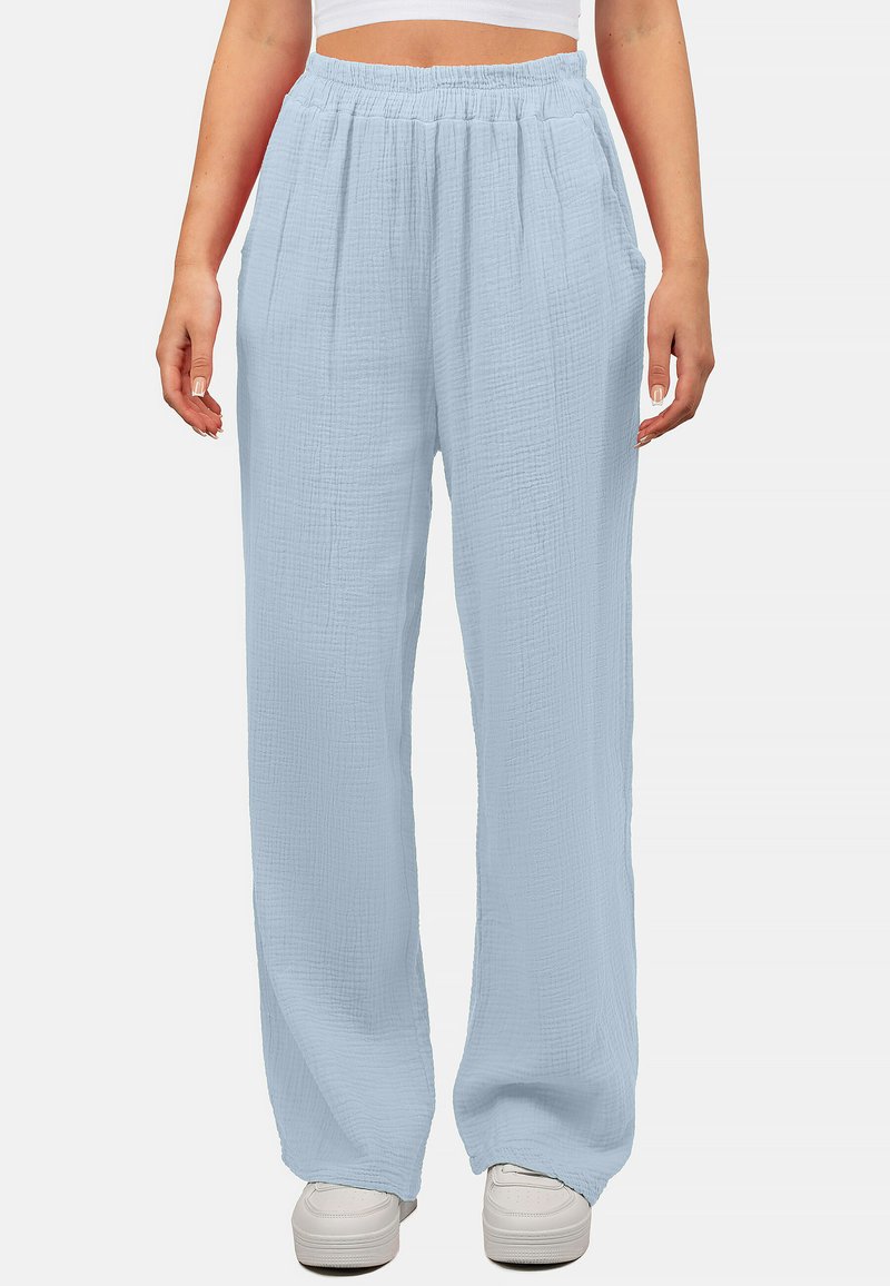 Lichtblauwe, wijde broek van een gestructureerde stof met een elastische tailleband en zijzakken, gecombineerd met witte sneakers.