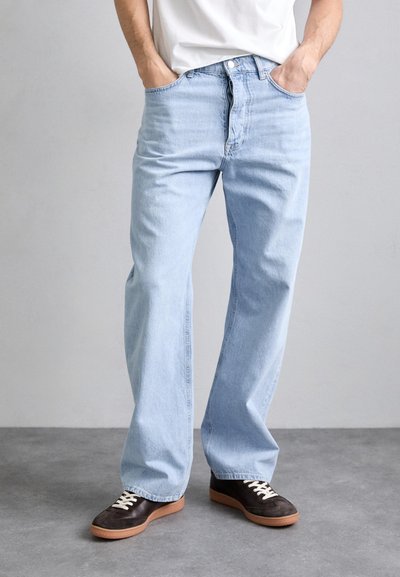 Jeans azzurri chiari, dal taglio morbido e dritto, con cinque tasche e chiusura con bottone standard, indossati con sneakers scure.