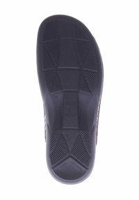 Schwarze Gummisohle mit strukturiertem Muster, die Rillen und Erhebungen für besseren Halt aufweist. In der Mitte befindet sich ein Logo.