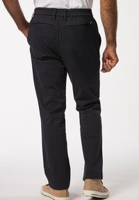 Granatowe spodnie elastyczne w pasie z dwoma tylnymi kieszeniami, prosty krój i gładka faktura, połączone z beżowymi butami wsuwanymi.