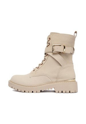Beżowe skórzane botki za kostkę na sznurówki z grubą gumową podeszwą, złotym paskiem z klamrą i pętelką na tyle.