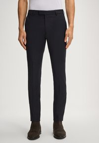 Marinefarbene Anzughose mit schlanker Passform und glatter Textur, mit flachem Bund, Gürtelschlaufen und seitlichen Taschen, kombiniert mit braunen Wildlederstiefeln.