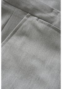 Grå tygbyxor med en slät textur, med sidofickor och fint sydda sömmar. Materialet verkar lätt och hållbart.