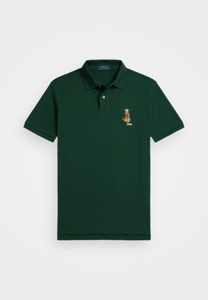 Camisa polo verde feita de algodão, com gola clássica, mangas curtas e um design de um cão bordado no lado esquerdo do peito.