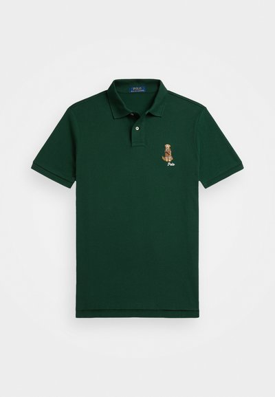 Camisa polo verde feita de algodão, com gola clássica, mangas curtas e um design de um cão bordado no lado esquerdo do peito.