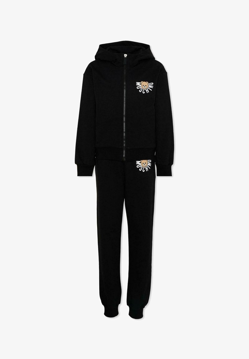 Completo con felpa nera con cappuccio e zip e pantaloni della tuta, con orsetto marrone e logo bianco "Moschino" sul petto e sulla coscia.