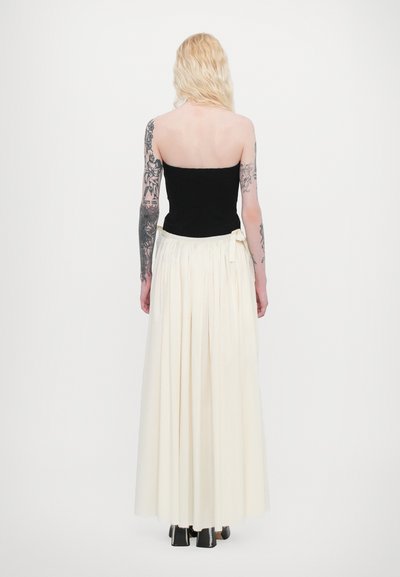Svart figursydd bodice med en strapless-design, i kombination med en flödande, knälång krämfärgad kjol med veck och en rosett vid midjan.