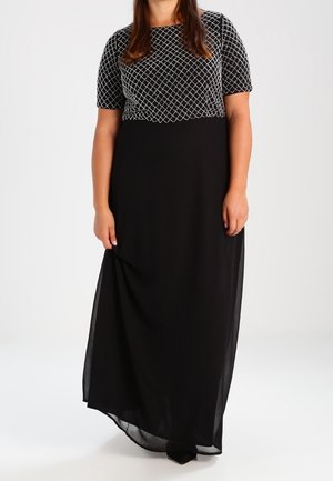 Robe longue noire avec un haut à manches courtes orné d'un motif losange. La jupe est fluide et superposée pour un effet texturé.