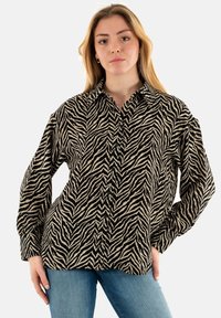 Camicia a stampa zebrica in bianco e nero, con colletto, maniche lunghe e chiusura a bottoni, dal taglio morbido. Tessuto testurizzato.